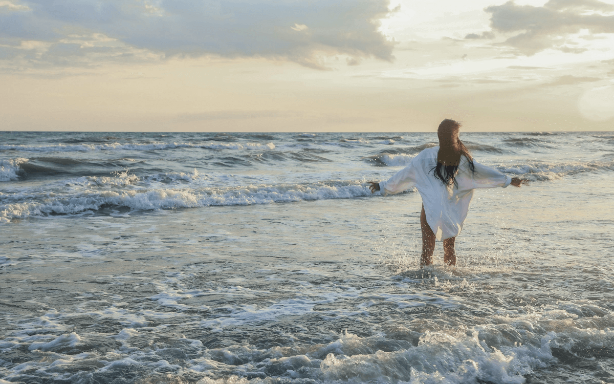 Woman standing in the ocean in a white shirt